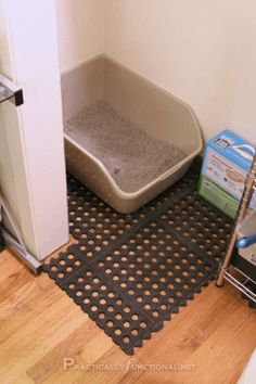 a cat litter box in the corner of a room next to a door and floor mat