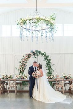 a bride and groom kissing in front of a floral arch