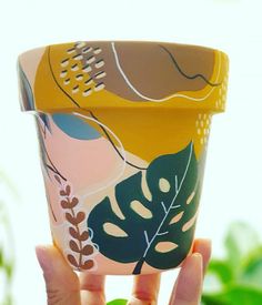 a hand holding up a cup with leaves on it