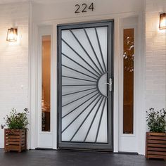 the front door to a home with two planters on either side and an open glass door