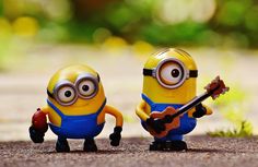 two minion figurines sitting next to each other with a guitar in their hands