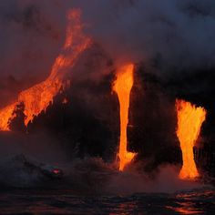 lava flowing into the ocean at night with bright orange light coming from it's stacks