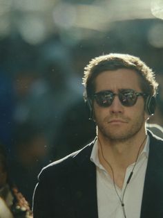 a man with headphones on walking in front of a group of people wearing sunglasses