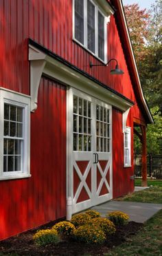 a black and white photo of a red barn with the doors open to let in light