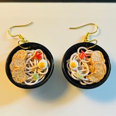 the earrings are decorated with noodles and fried eggs