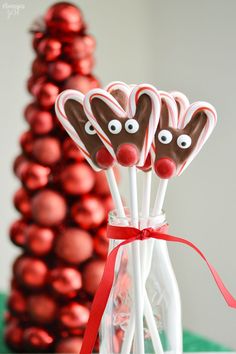 some candy sticks with googly eyes on them are in front of a red christmas tree