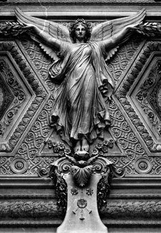 an ornate statue on the side of a building in black and white with angel wings