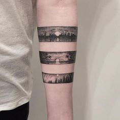 a person with a tattoo on their arm that has trees and mountains in the background