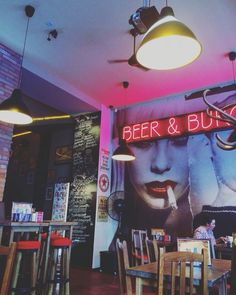 the inside of a restaurant with tables and chairs, neon signs on the wall above them