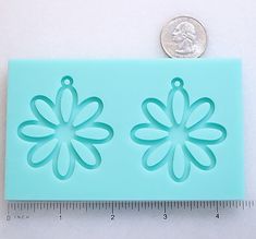 a penny is sitting next to a blue plastic flower mold that looks like it has been cut out