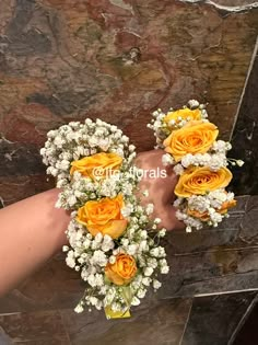 three yellow roses and baby's breath are arranged in the palm of someones hand