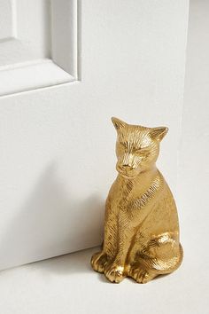 a gold cat figurine sitting next to a white door