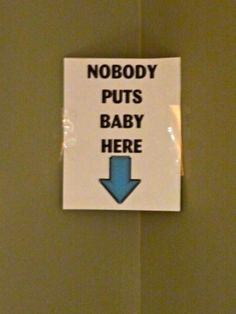 a sign that says nobody puts baby here on the wall in front of a toilet