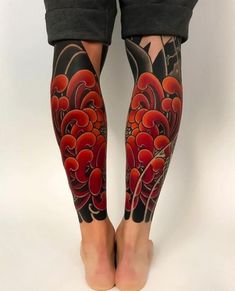 the legs and ankles of a woman with red flowers on her leg, both covered in black