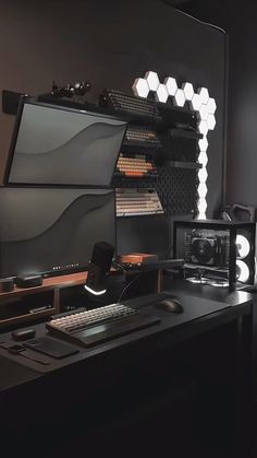 a desk with a monitor, keyboard and other items on it in front of a mirror