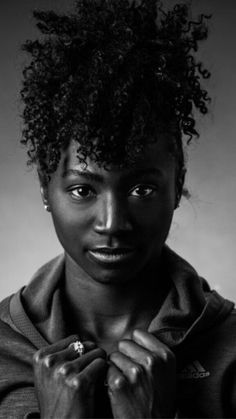 a black and white photo of a woman with her hands on her chest looking at the camera