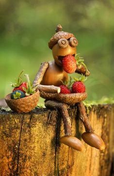 a small figurine sitting on top of a tree stump with strawberries in it