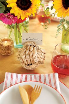 a place setting with sunflowers and flowers in vases