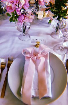 the table is set with pink flowers and silverware