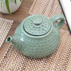 a ceramic teapot sitting on top of a table next to a potted plant