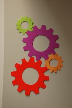 three colorful gears are hanging on the wall