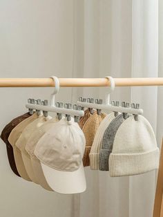 four hats hanging on a rack in front of a window