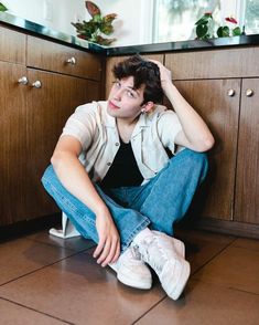 a young man sitting on the floor with his head in his hands