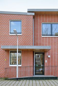 a red brick building with two windows and a street light in front of the door