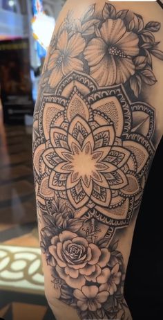 the back of a woman's arm with an intricate flower tattoo on her shoulder