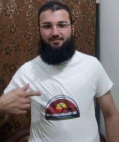 a man with a beard and glasses pointing at the camera while wearing a t - shirt