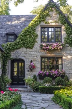 a stone house covered in flowers and greenery