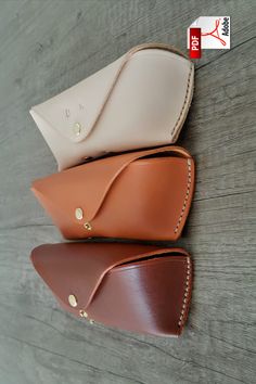 three purses sitting on top of a wooden table next to each other, one in white and the other in brown