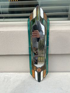 a man is taking a selfie in the reflection of a stained glass wall mirror