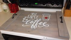 a stove top with the words cut first coffee written in white paint on it next to an oven door