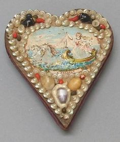 a heart shaped box with an image of a boat on the water and pearls around it