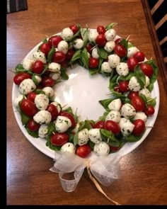 a wreath made out of tomatoes and mozzarella on a white plate with ribbon