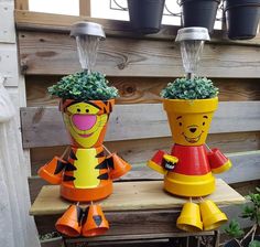 two winnie the pooh planters sitting on top of a wooden table