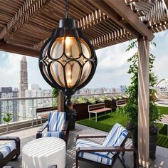 an outdoor patio with chairs, table and lamp hanging from it's roof over looking the city