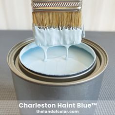 a brush with white paint on top of it sitting in a metal can that is painted blue