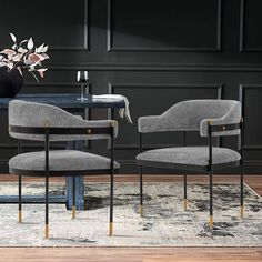 two grey chairs sitting on top of a rug in front of a table with a vase