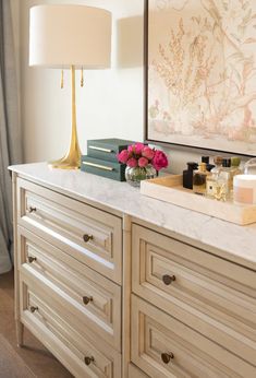 a white dresser topped with lots of drawers next to a wall mounted art piece on top of it