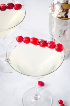 two glasses filled with white wine and cranberry garnish on the rim