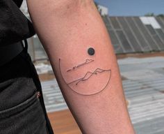 a person with a tattoo on their arm that has a mountain and sun in it