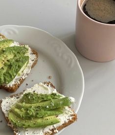 two pieces of toast with avocado on them and a cup of coffee