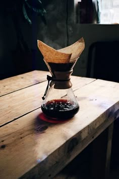 an old coffee pot sitting on top of a wooden table