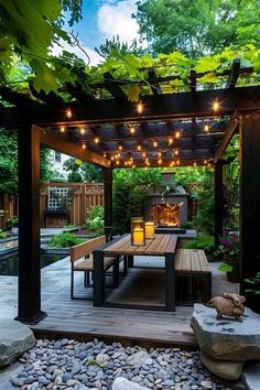 an outdoor dining area is lit up by string lights and surrounded by rocks, trees, and plants