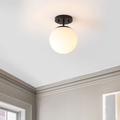 a light that is on the ceiling above a bed in a room with white walls