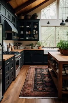 a kitchen with black cabinets and wooden flooring has a rug on the floor in front of it