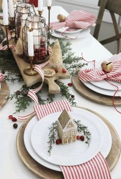 the table is set for christmas with plates and napkins on it, candlesticks and ornaments