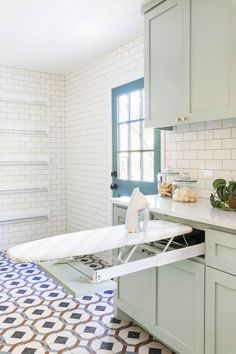 an ironing board in the middle of a kitchen with blue and white tiles on the floor